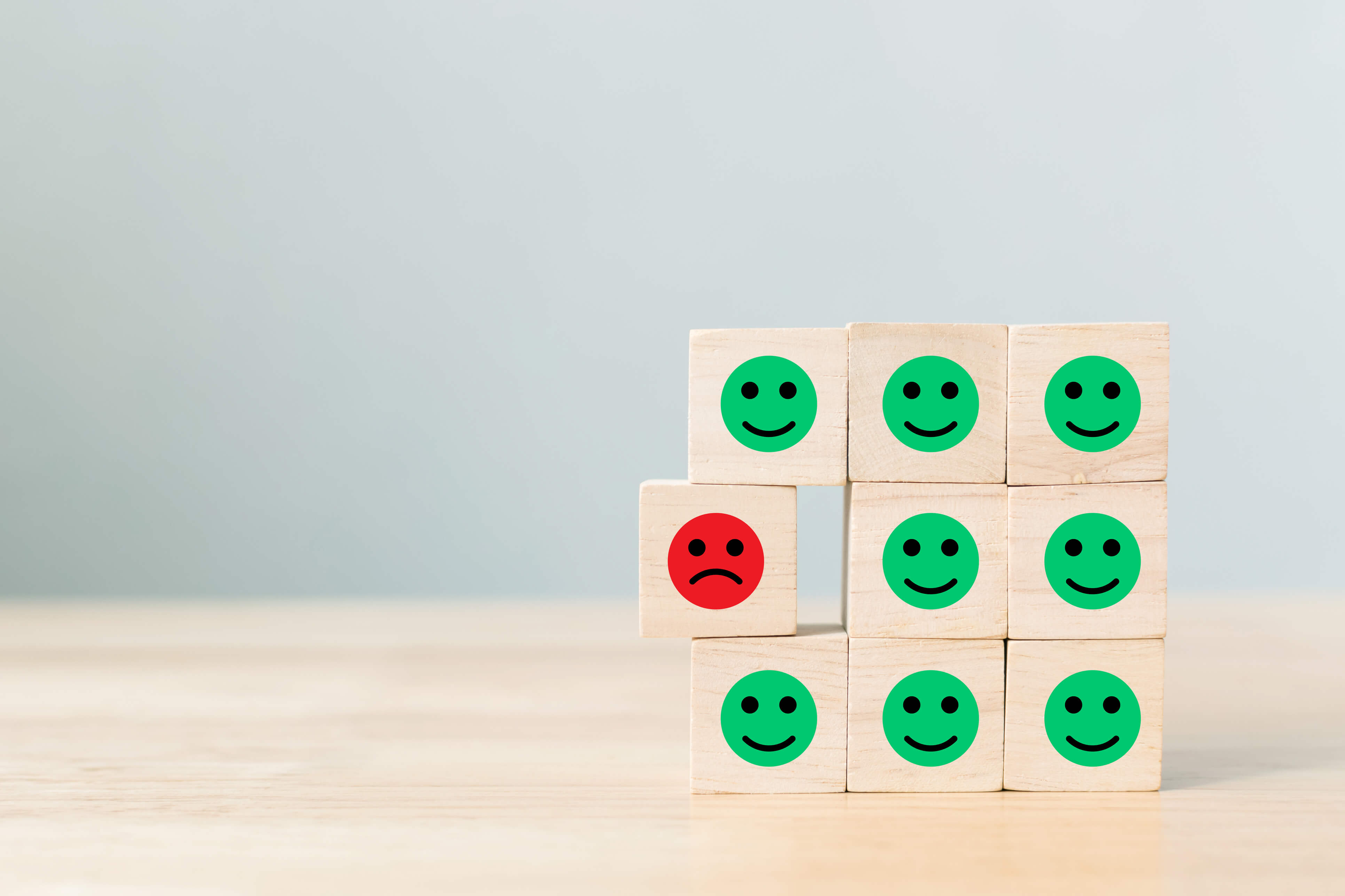 Happy faces on wooden blocks with one upset face