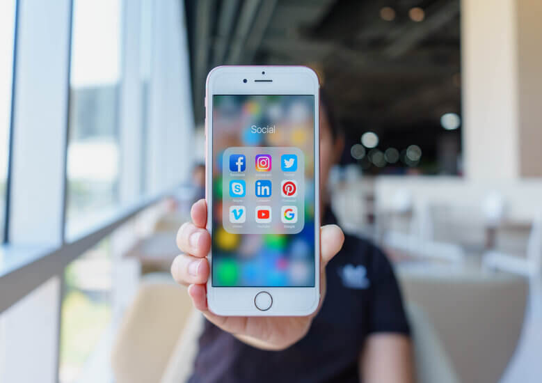 Person holding up mobile phone showing social media apps